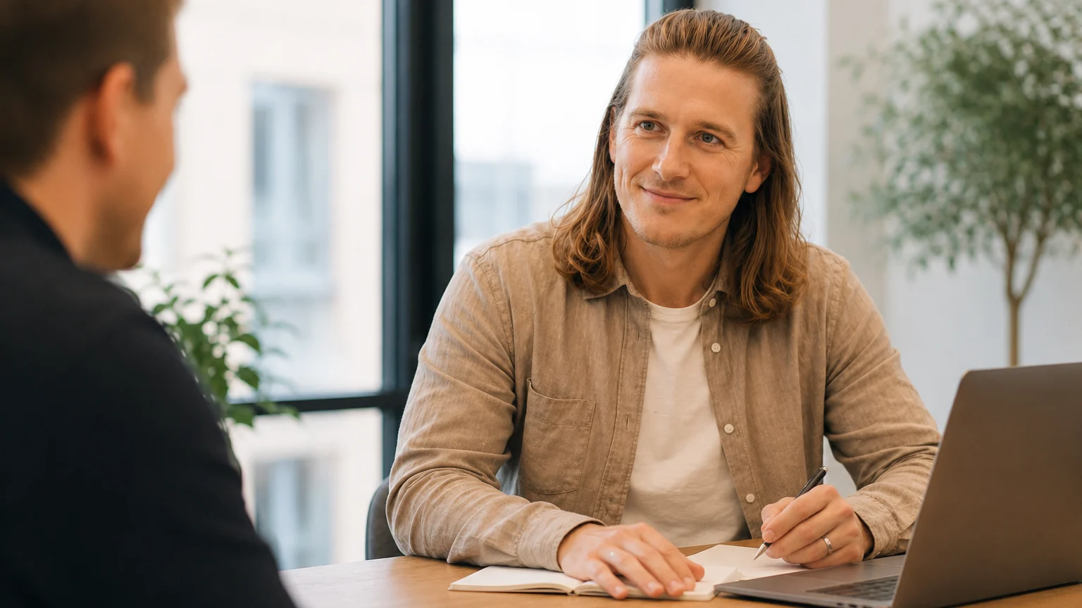 Mads Clausen sidder ved et mødebord med en kunde og en åben laptop